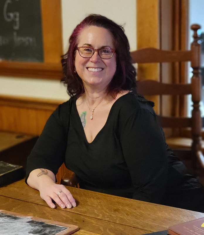 Susan McCarthy, professional organizer and founder of A Less Cluttered Life sitting at an old fashioned desk, representing her former career as a teacher.